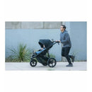 Jogging stroller BOB – Wayfinder, Nightfall model, being pushed by a man while jogging, with a child inside.