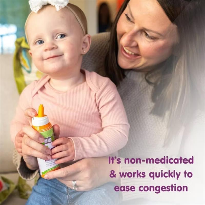 A smiling toddler holding a bottle of Boogie Mist for stuffy noses, with a woman joyfully interacting with her.