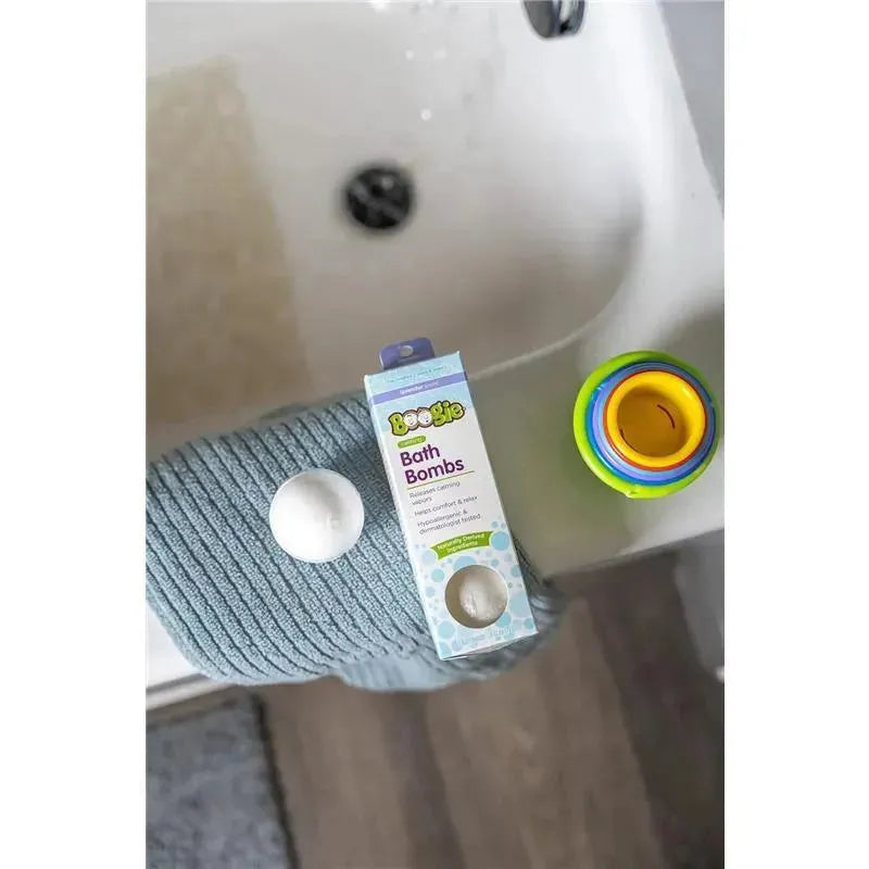 Boogie Wipes Kids Bath Bombs packaging next to a bath bomb and a colorful bath toy on a soft towel.