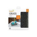 Boon GRASS countertop drying rack in grey, featuring leaf-like spikes and blue bottle accessories on a tabletop.