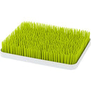 Countertop drying rack featuring green grass-like spikes on a white base, designed for drying dishes and utensils.