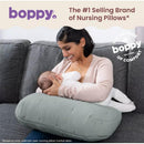 Boppy Nursing Pillow Luxe in sea green, supporting a mother nursing her baby on a gray couch.