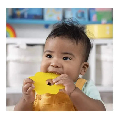 Baby chewing on a yellow flower-shaped teether from the Bright Starts - 2Pk Sun & Popsicle Soothers, with a playful expression.