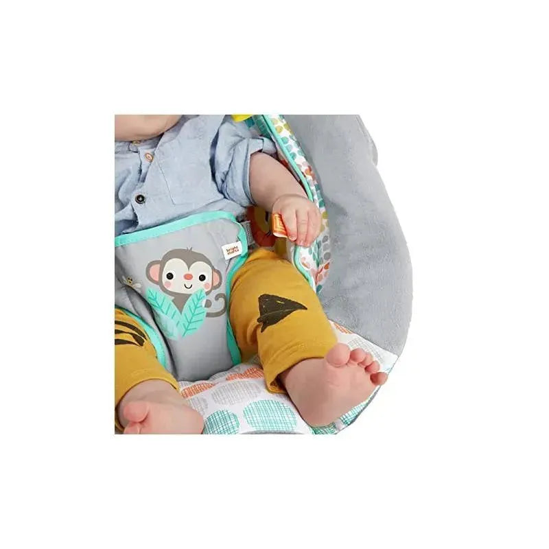 A baby sits in the Bright Starts Whimsical Wild Cradling Bouncer, wearing yellow pants with a shark design and a light blue shirt.