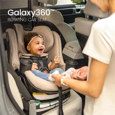 Britax Galaxy360 Slim Rotating Convertible Car Seat in teak color, featuring a smiling child and an adult securing her in the seat.