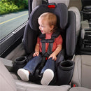 Child safely seated in a Britax One4Life All in One Convertible Car Seat in Parchment color, smiling with seatbelt securely fastened.