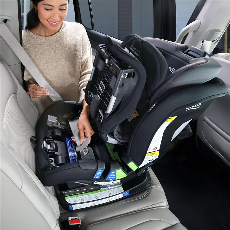 A woman secures a Britax Poplar Convertible Car Seat in Stone Onyx using a seatbelt in a vehicle.