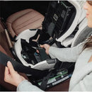 A woman secures the Romer Veni Convertible Car Seat in a vehicle, showcasing its safety belt installation feature.
