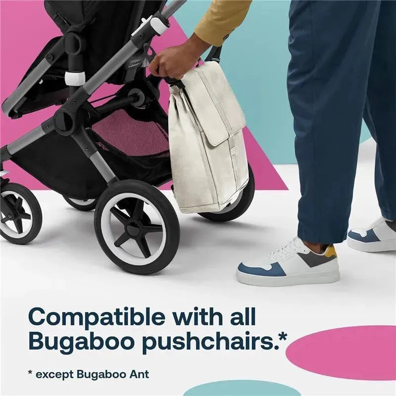 Water-repellent Bugaboo changing backpack in Desert Taupe, held next to a pushchair, compatible with all Bugaboo models except Ant.