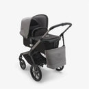 Grey melange Bugaboo changing bag attached to a stroller with a seat and hood, showcasing a modern design and utility features.