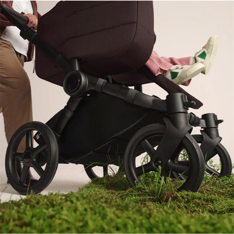 Bugaboo Donkey 6 Complete Stroller in Black/Cocoa Brown with a child’s feet visible, set against a grassy backdrop.