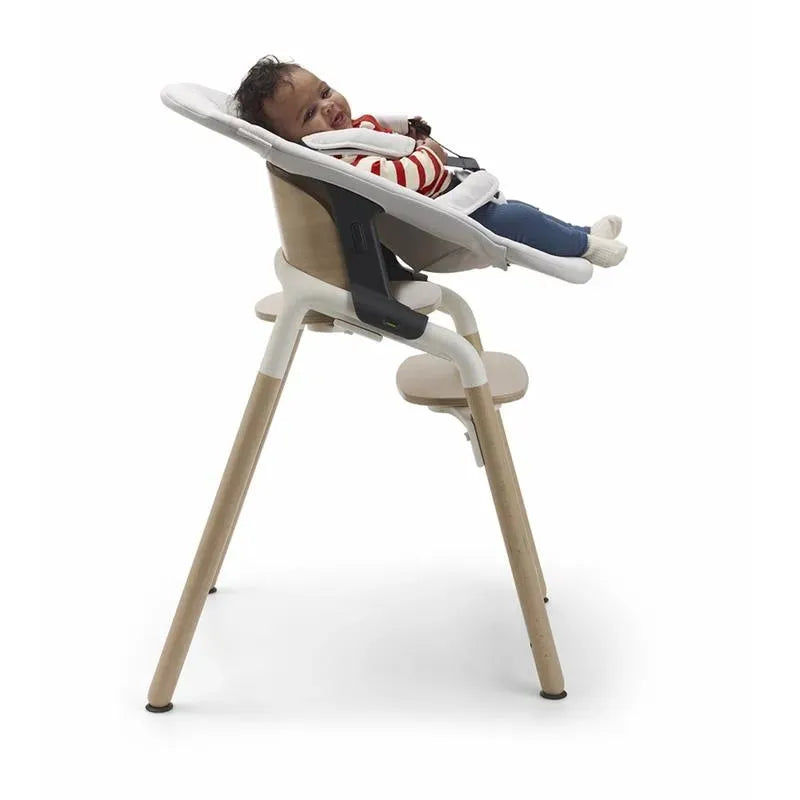 Bugaboo Giraffe Newborn Set in Tornado Grey with a smiling baby reclining in the high chair.