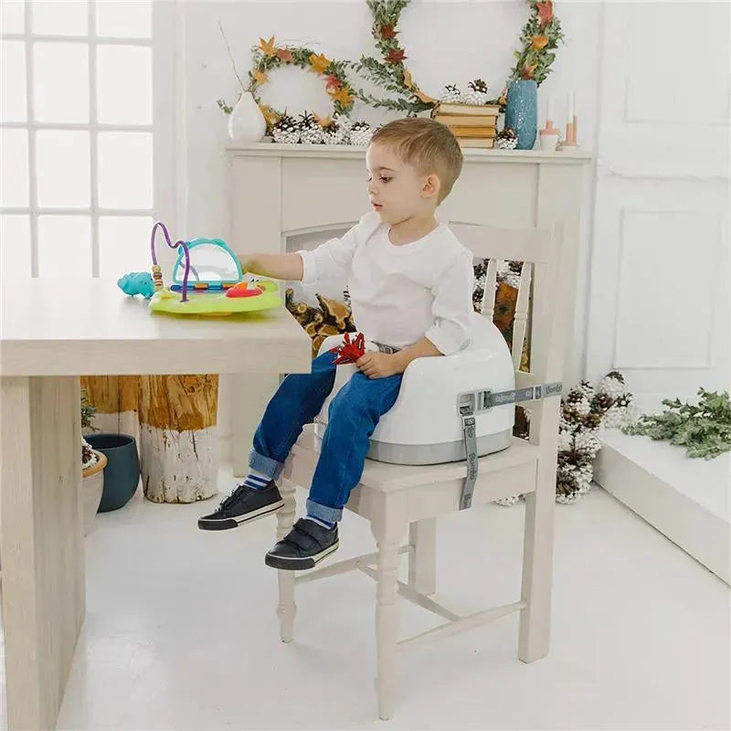 Child seated in a Bumbo taupe adjustable height 3-in-1 multi-seat at a table, playing with a colorful activity toy.