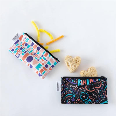 Reusable snack bags in colorful designs with phrases promoting kindness, accompanied by snacks and heart-shaped bread.