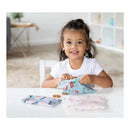 A child smiles while holding a blue Disney Princess snack bag, with two more bags and snacks on the table.