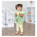 Bumkins Disney Ruffle Apron Bib featuring Tiana design, worn by a smiling child with pigtails, clapping hands.
