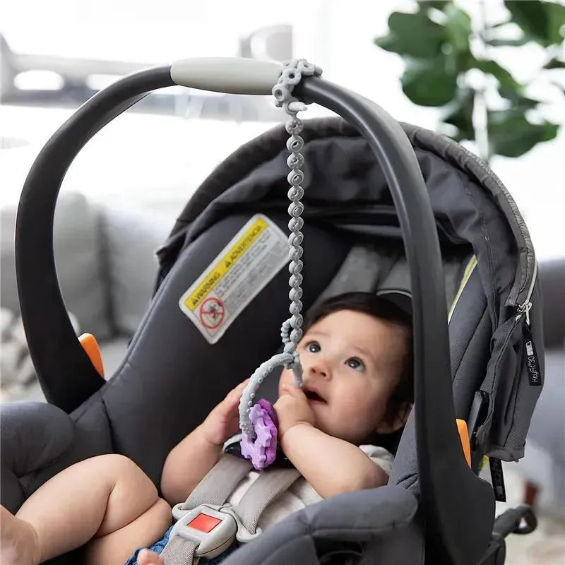 Gray silicone accessory tethers attached to a baby car seat, with an infant playing and holding a teething toy.