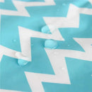 Water droplets on a blue bib with a white zigzag pattern, demonstrating its waterproof feature.