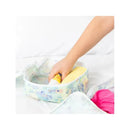 Packing cube from Bumkins, Aloha design, with a hand placing a yellow item inside, surrounded by colorful clothing.