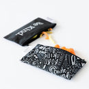 Reusable snack bags in black with white designs, featuring positive phrases, filled with colorful snacks.