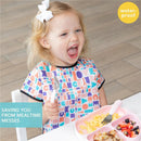 Short sleeve bib featuring colorful letters and shapes worn by a smiling child holding a fork, with a pink divided plate of food.