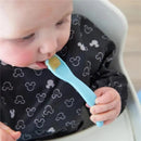Baby eating with a light blue silicone spoon from a Mickey Mouse-themed feeding set, wearing a waterproof bib.
