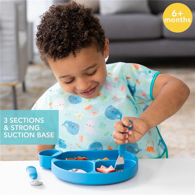 Silicone grip dish in dark blue with three sections and a strong suction base, being used by a toddler.