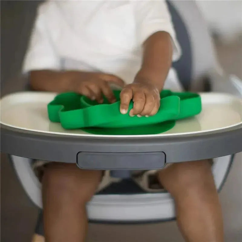 Bumkins silicone grip dish in dinosaur shape, being handled by a child at a high chair.