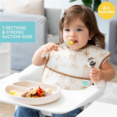 Bumkins Silicone Grip Dish in sand color with three sections, used by a toddler eating with a fork.