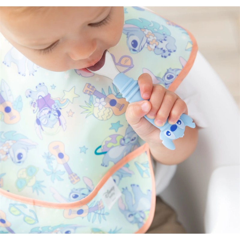 Bumkins Spoon and Fork set in blue with a Stitch design, held by a toddler wearing a colorful bib featuring Stitch patterns.