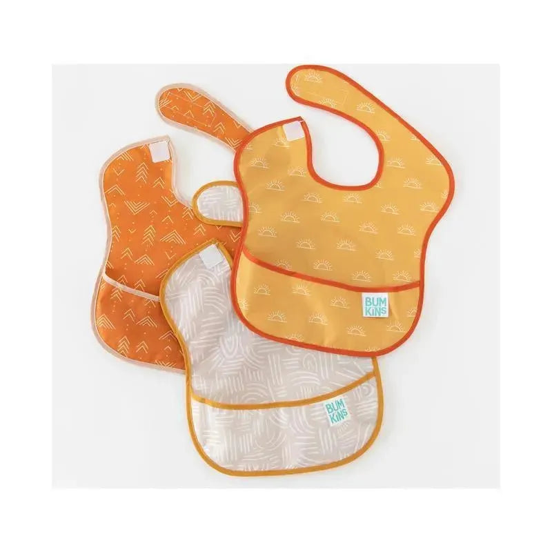 Three Bumkins SuperBib bibs in desert boho patterns, featuring orange hues and playful designs, stacked together.