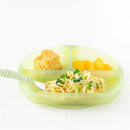 Silicone suction plate in green jelly color with three divided sections, holding pasta, broccoli, and fruit.