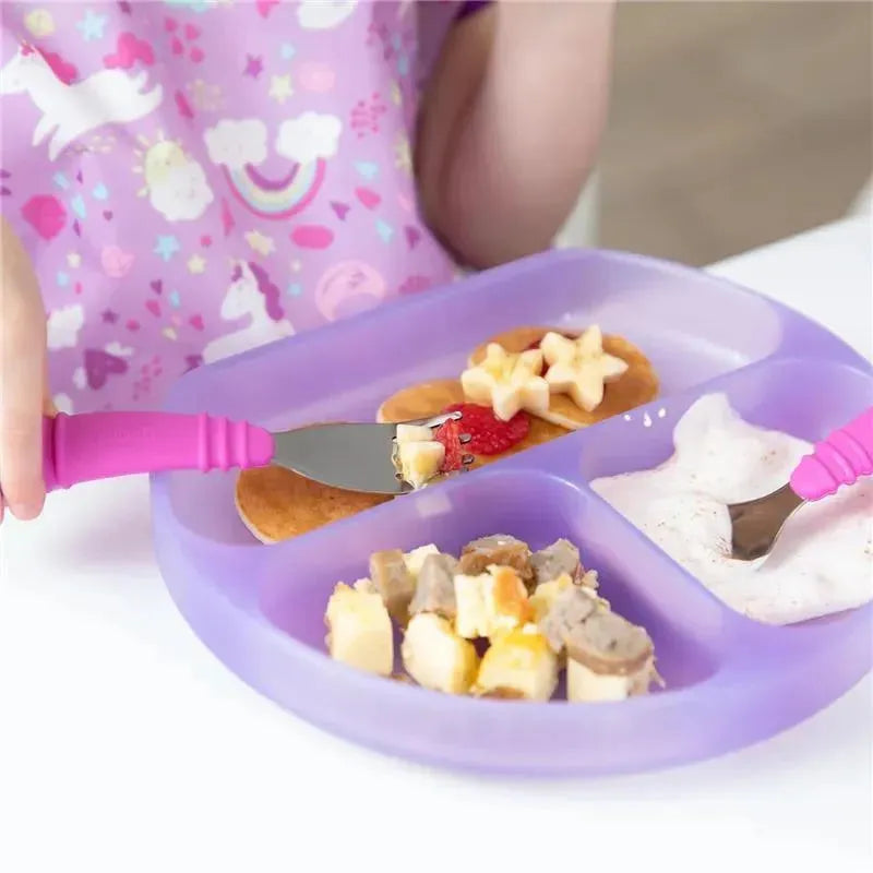 Purple silicone dish with three sections filled with pancakes, fruit, and yogurt, being eaten by a child using pink utensils.
