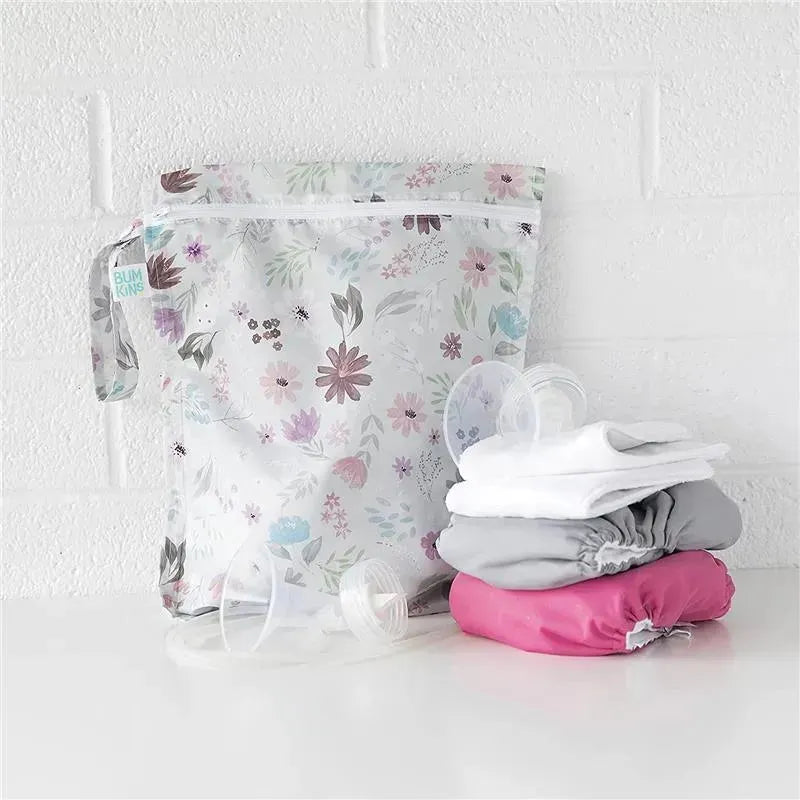 Waterproof floral wet bag from Bumkins, displayed with stacked baby products and circular items beside it.