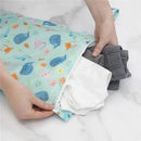 Waterproof Bumkins wet bag in ocean-themed design, partially unzipped with folded clothes inside.