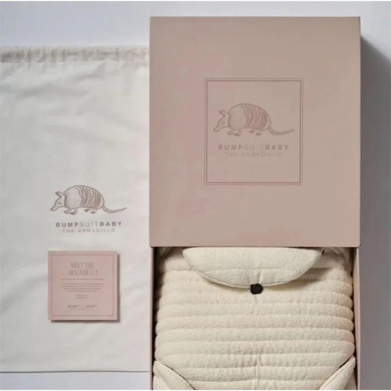Bumpsuit The Armadillo Baby Carrier in packaging, featuring a soft cream-colored carrier and a branded box.