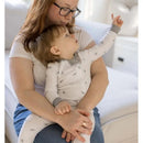 Child in a bee-patterned Burts Bees sleep & play outfit, being held lovingly by an adult on a couch.