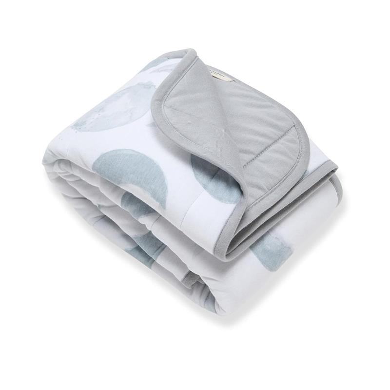 Reversible quilted blanket in Quarry design, featuring a light gray outer with blue watercolor circles.
