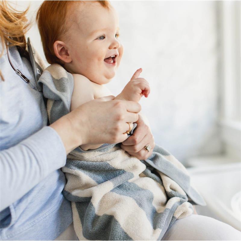 A joyful baby wrapped in a rugby striped towel, held by an adult, smiling and pointing.