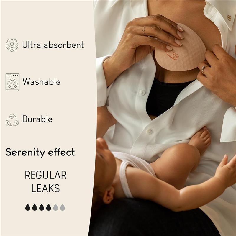 White nursing pad being applied by a person wearing a black top and white shirt, with a baby nearby. Text highlights features: ultra absorbent, washable, durable, regular leaks, serenity effect.