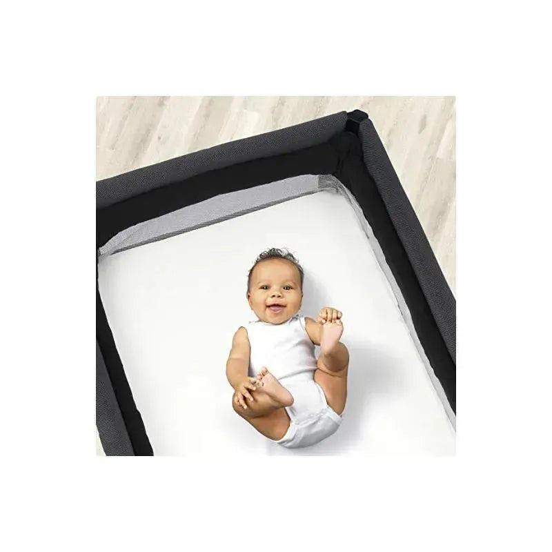 Chicco 2 Pack Lullaby Playard Sheets in white with a smiling baby in a playard, showcasing a safe and comfortable sleep space.
