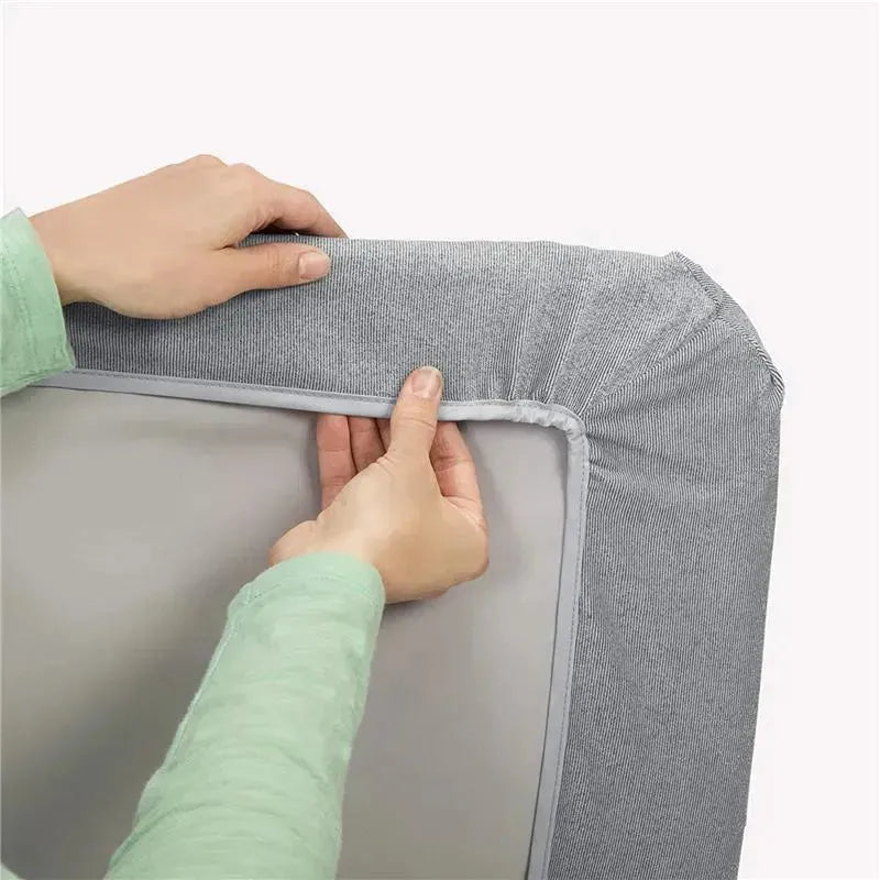 Hands adjusting a grey triangle-patterned bassinet sheet on a mattress, showcasing the Chicco - 2Pk Lullago product.