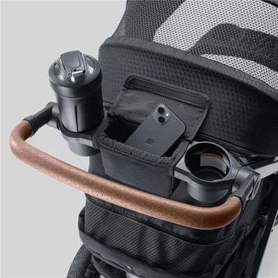Chicco Bravo Primo ClearTex Trio Travel System handle with cup holder, phone pocket, and a textured brown grip.