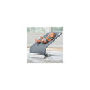 Chicco E-Motion Auto-Glider & Bouncer in grey with a baby comfortably seated, hands raised, on a light rug near a window.