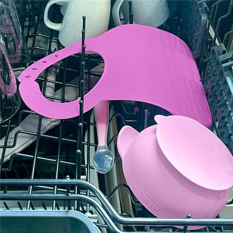 Silicone feeding accessories in a dishwasher: pink bib, bowl, and spoon from the Chicco Easy Start set for 6M+.