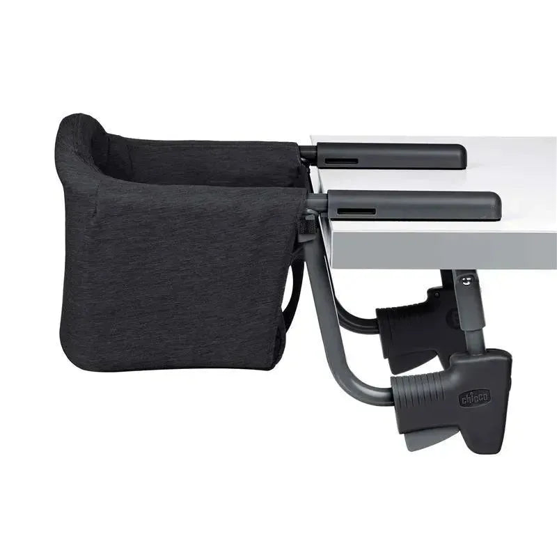 Chicco FastLock Hook-On High Chair in black attached to a table, featuring adjustable clamps for secure attachment.