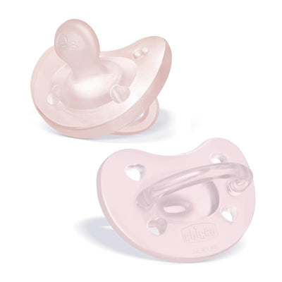 Two Chicco Physioforma orthodontic silicone pacifiers in soft pink, designed for infants 0-6 months, featuring heart-shaped holes and a clear handle.