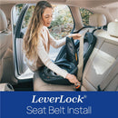 A woman installs a Chicco Fit360 Zip ClearTex Rotating Convertible Car Seat using the LeverLock seat belt system in a car.