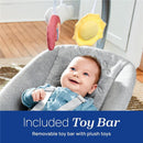 Baby in a gray Chicco Float Baby Seat smiles while reaching for a removable toy bar featuring plush cloud and sun toys.