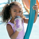 Toddler with curly hair holds a Chicco insulated straw sippy cup, decorated with a floral purple print, at a playground.